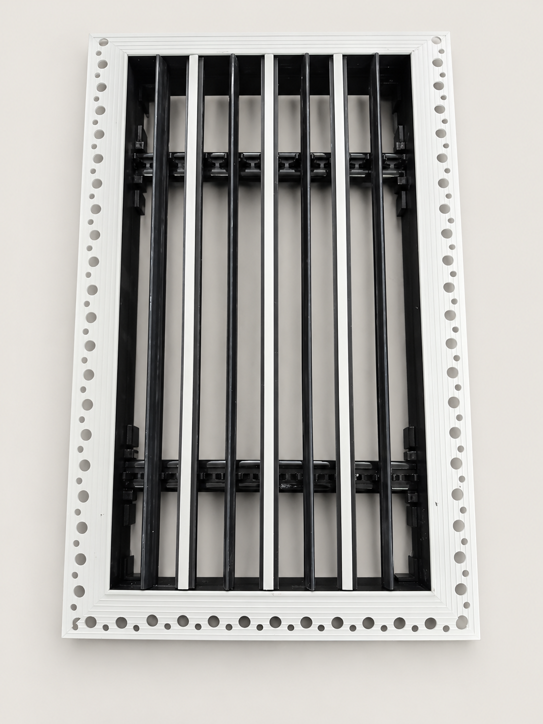 Plaster-in linear diffuser flange, perforation ring at the perimeter where joint mesh and skim coat key into the edge